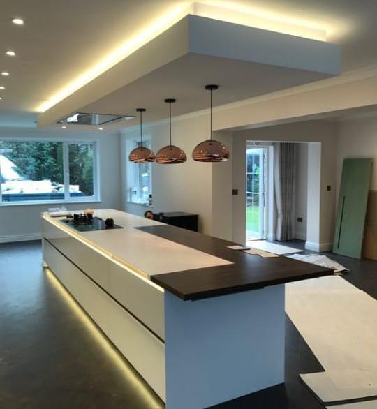 Ilha de gesso suspensa com sanca invertida e iluminação indireta em LED, ideal para cozinhas americanas e ambientes integrados de alto padrão.